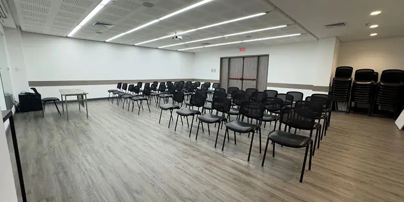 Auditorio de Ayurá Center con sillas negras en filas, piso de madera e iluminación LED