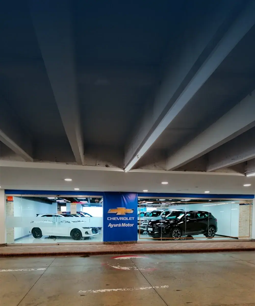 Vitrina de Ayurá Motor de noche vista de frente, con techo azul y carros exhibidos